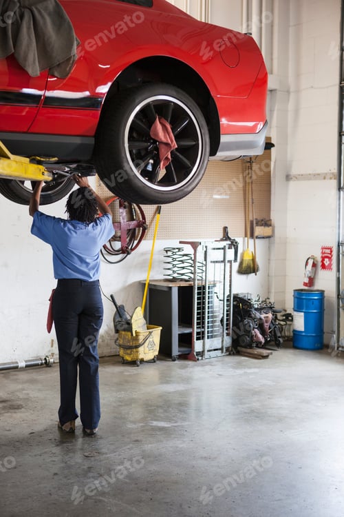 Preview: Mechanic in a repair shop works on the underside of a car up on a lift