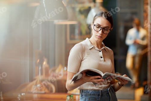 Preview: Intelligent lady reading magazine in cafe