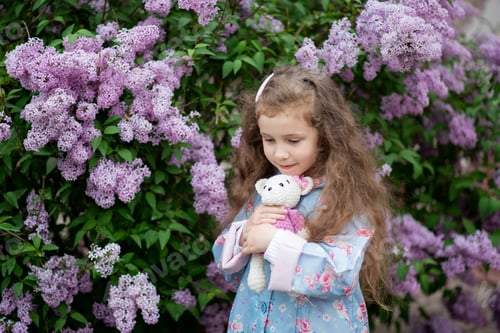 Preview: A cute girl next to a bush of blooming lilacs.