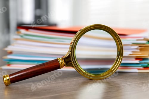 Preview: Magnifying glass and many folders with documents on wooden desk, closeup