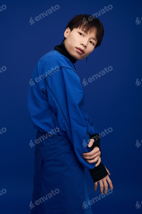 Preview: A young, handsome asian man stands confidently in a stylish outfit with a vivid blue background