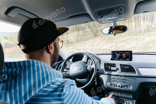 Preview: Man driving car while being on a day road trip.