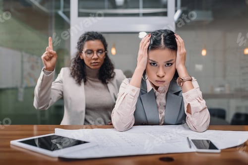 Preview: stressed multiethnic businesswomen working with documents in office