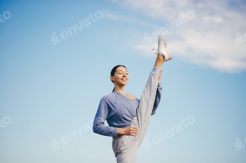 Preview: Athletic Woman Doing Leg Split Exercise Outdoors