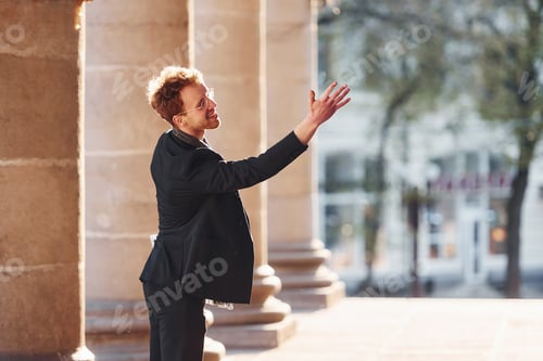 Preview: Talking to someone. Elegant young man in formal classy clothes outdoors in the city