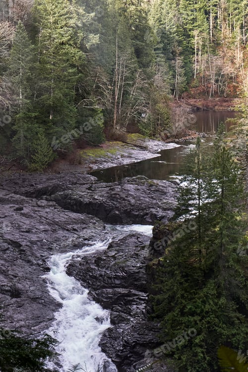 Preview: View of the top of Elk Falls as the river rushes through the flat brown rocks.