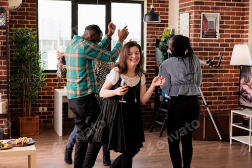 Preview: Multiethnic group of closed friends dancing together in living room at wine party while having fun