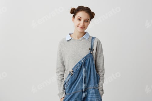 Preview: Young adorable woman looking on camera in casual denim jumpsuit. Affable brunette lady with hair in