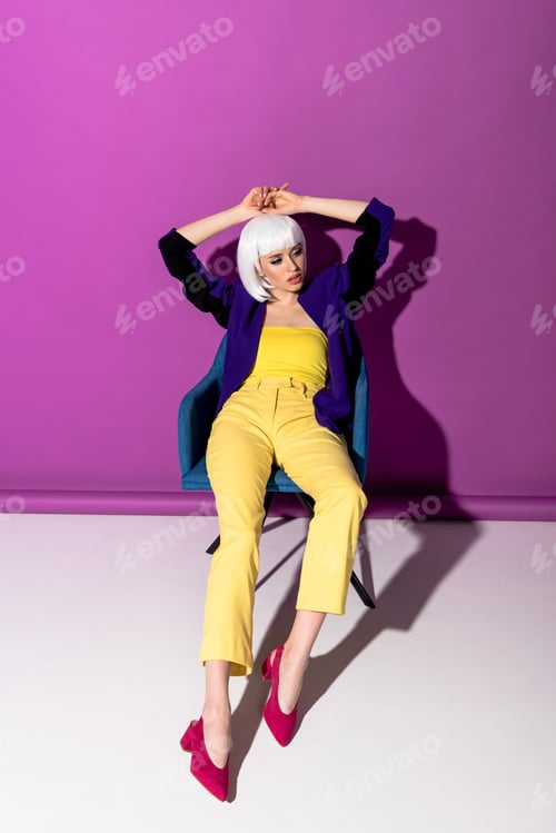 Preview: Gorgeous young woman in white wig posing in armchair on purple background