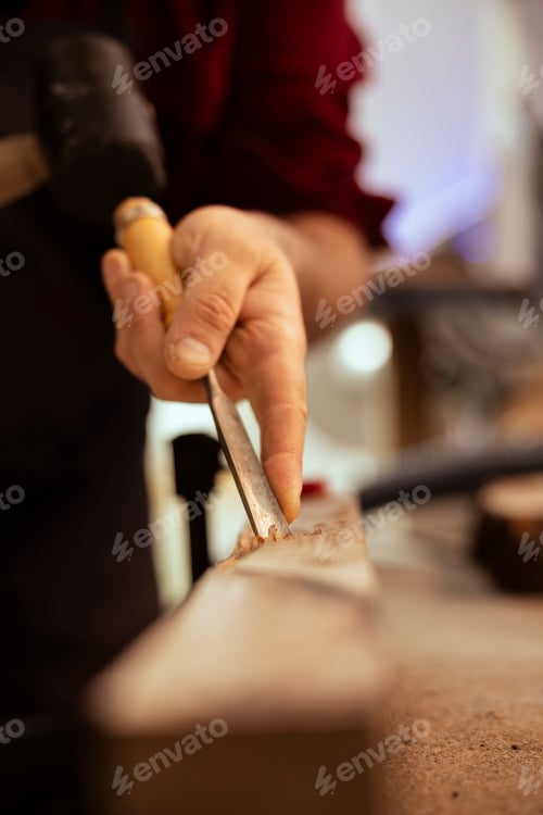 Preview: Man using traditional crafting process to shape wooden pieces