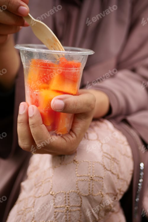 Preview: women eating papaya and grape from a plastic take away container