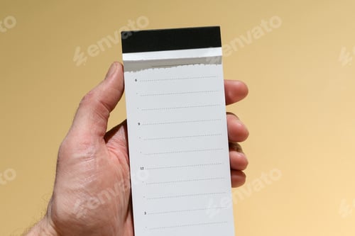 Preview: Male hand holds blank tearoff daily planner on warm yellow background