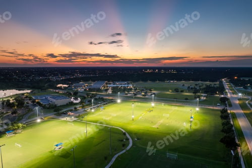 Preview: Public sports stadium with young people playing football game at sunset. Active way of life concept