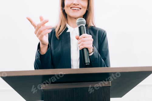 Preview: cropped image of smiling speaker gesturing and talking at podium tribune during seminar in