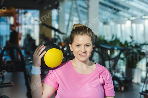 Preview: smiling overweight woman with medicine ball on shoulder