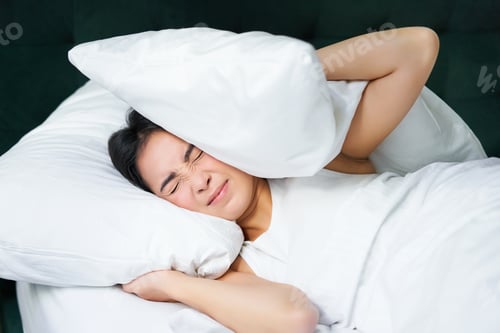 Preview: Sad girl with insomnia. Young asian woman lying in bed, cover her ears with pillow, cant sleep