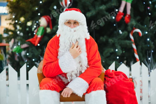 Preview: Santa Claus sitting on a chair near the Christmas tree in the mall