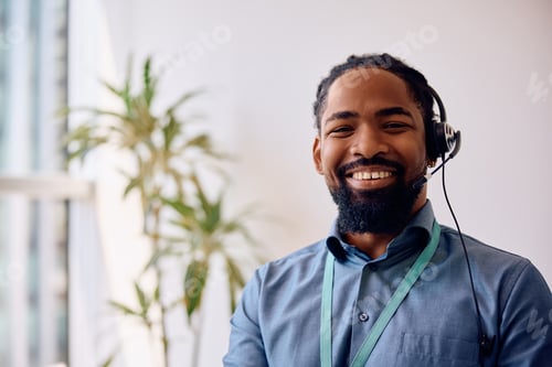 Preview: Happy black call center agent at work looking at camera.