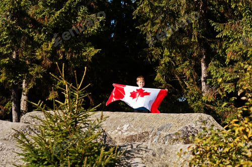 Preview: Happy Canada Day. Boy with large Canadian flag celebration in mountains.