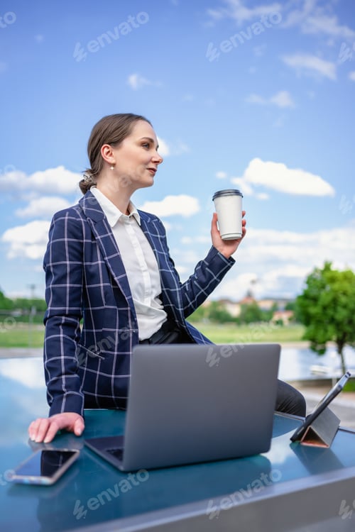Preview: Businesswoman using devices on street