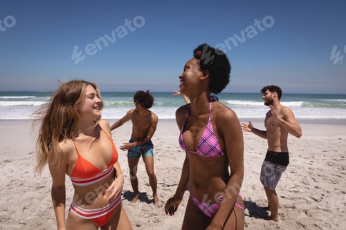 Preview: Front view of happy group of multi ethnic friends dancing together on beach in the sunshine