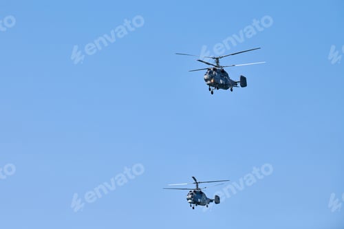 Preview: Two military helicopters flying in bright blue sky performing demonstration flight, aerobatic team