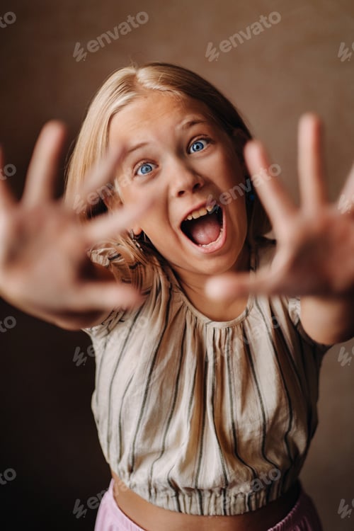Preview: A happy child, a little girl in a gray T-shirt on a beige background