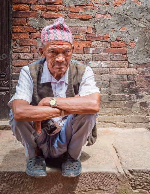 Preview: NEPAL, BHAKTAPUR - AUGUST 19, 2014: Positive aged man holding plank near equipments on staircase