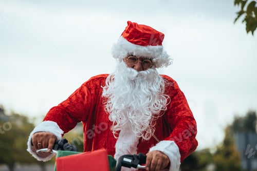 Preview: Santa Claus with gifts in the bicycle and his red suitcase on his back. Christmas time