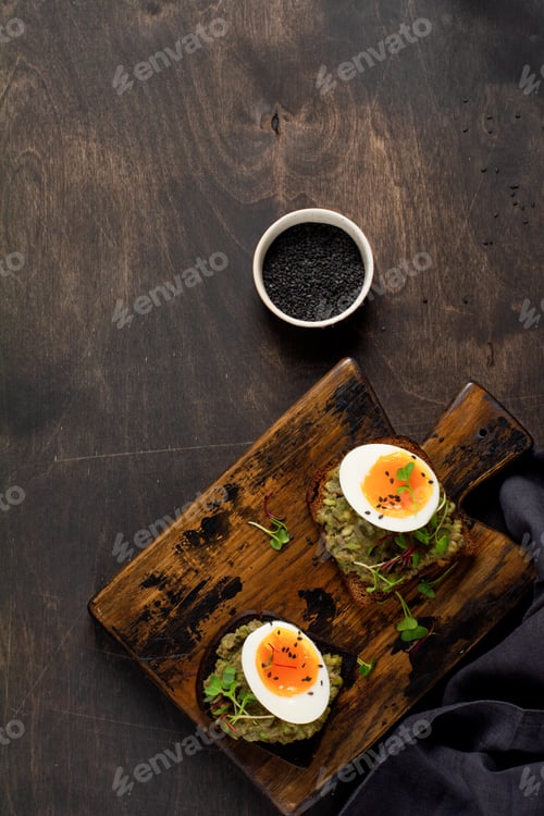 Preview: Healthy sandwich with avocado, eggs and microgreens on toast on a serving plate for breakfast. Healt