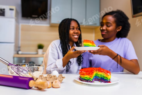 Preview: Happy loving same sex couple is preparing the rainbow pastry in the kitchen