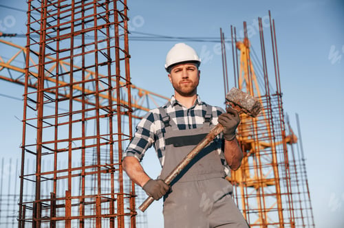 Preview: With big hammer in hands. Man is working on the construction site at daytime