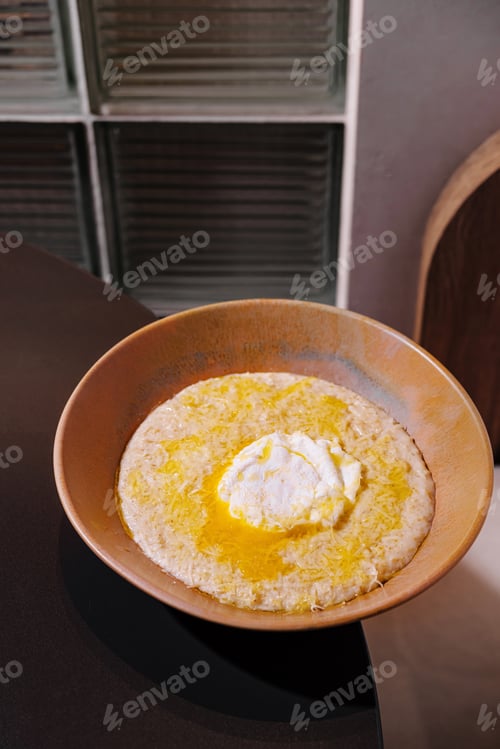 Preview: Bowl of creamy polenta with butter and cheese being served in restaurant setting