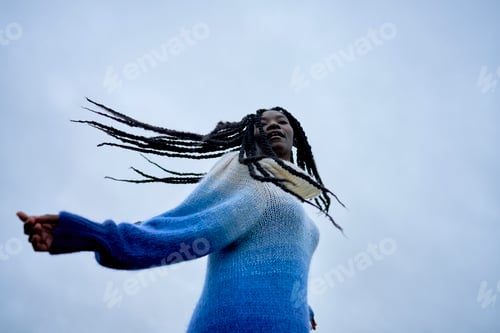 Preview: A joyful woman with long braids wearing a blue sweater
