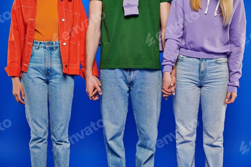 Preview: alternative family, cropped view of three polygamy people, young man and women holding hands