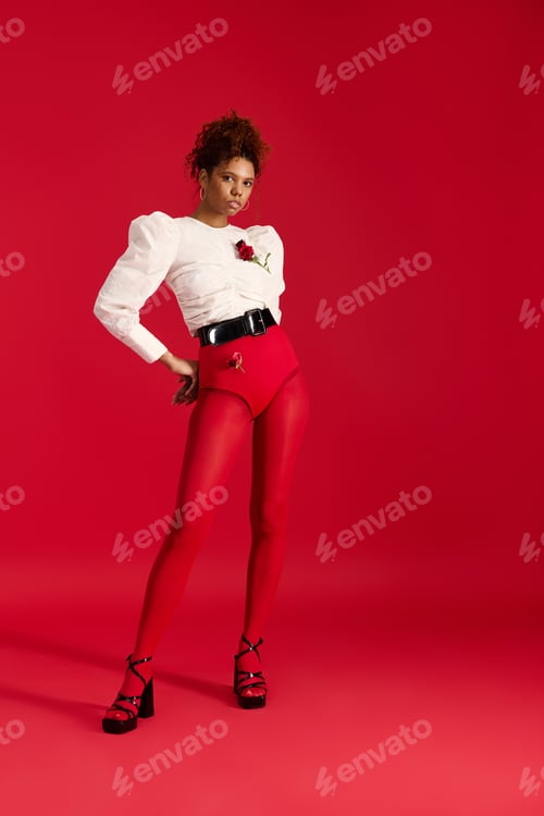 Preview: Beautiful woman in stylish red attire poses confidently against a vibrant backdrop