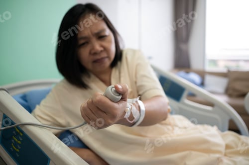 Preview: Middle-aged Asian female patient recovering from illness in hospital room, health care concept.