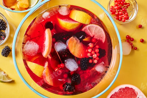 Preview: Top view on glass jug with homemade fruit berry drink with ice cubes on yellow background