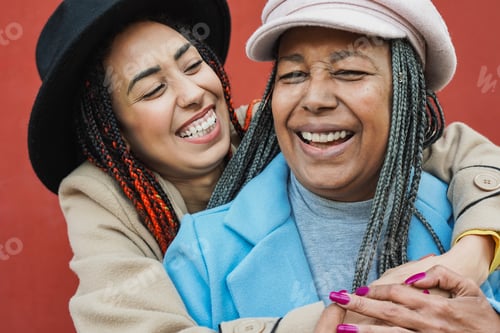 Preview: Happy african mother and daughter having fun together during winter time hugging each other