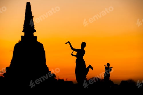 Preview: Silhouette women take Thai dancing to respect buddha and ancient pagoda in temple at sunset time.