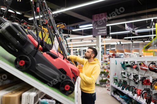 Preview: male buyer chooses a scarifier in a gardening equipment store