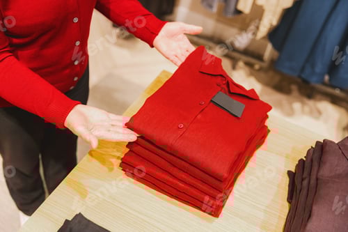 Preview: Senior women in red blouses choose new clothes in a boutique.