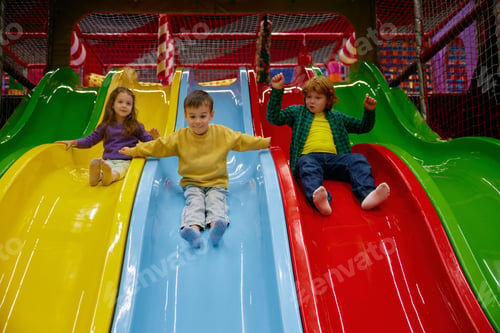 Preview: Happy children riding slide together at indoor play center