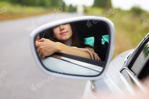 Preview: A young girl driving a car, the girl looks in the side mirror. Delivery for the right to drive a car