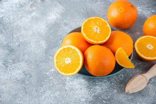 Preview: A bowl full of sliced and whole juicy orange fruits with wooden reamer