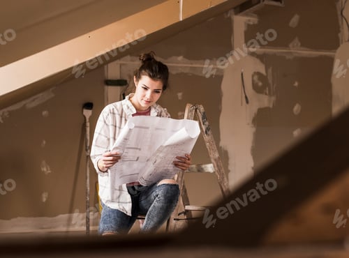 Preview: Young woman renovating her new home, holding construction plan