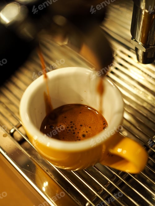 Preview: a coffee machine pours espresso coffee into a small yellow mug in a cafe