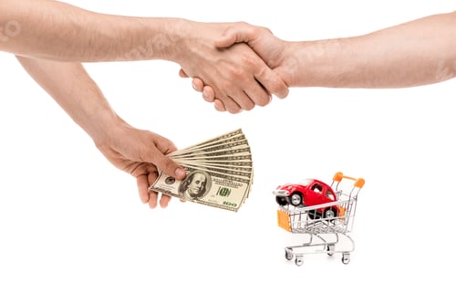 Preview: cropped view of men with dollar banknotes shaking hands near toy car in shopping cart isolated on
