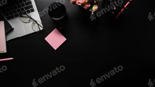 Preview: Laptop computer, sticky note coffee cup, glasses and supplies on black table.