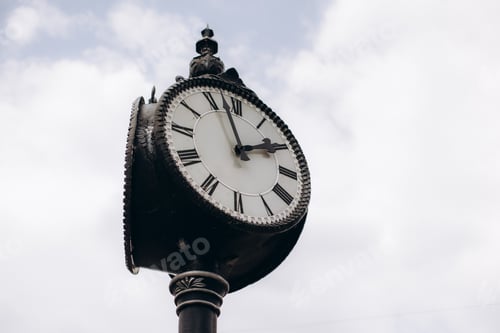 Preview: Vintage street clock displaying roman numerals against sky